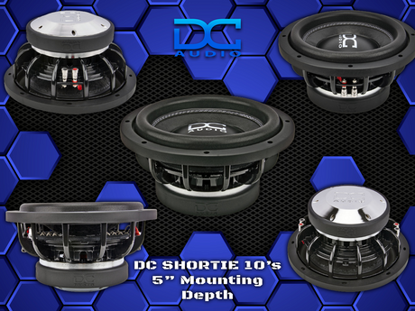 A collection of DC Audio Shortie subwoofers in various orientations, showcasing the speakers' design and the DC Audio logo.